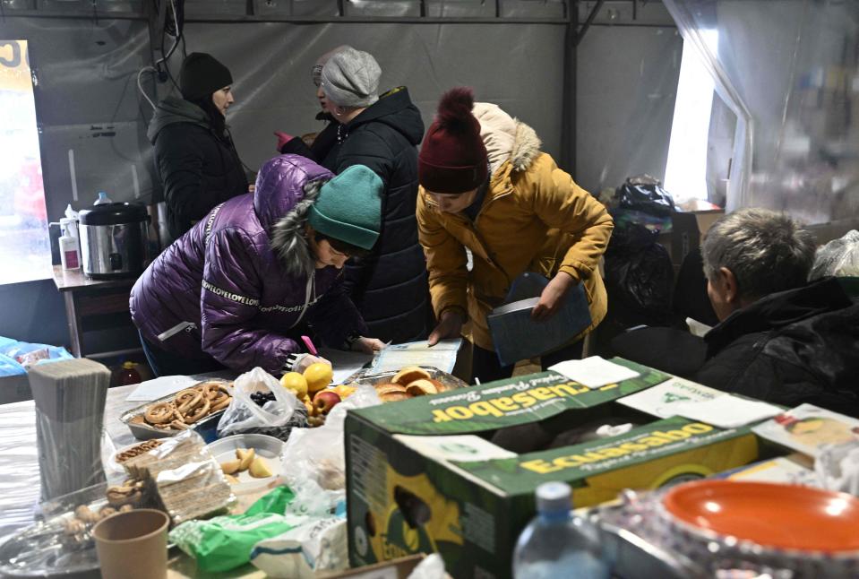 Ukrainians visit a tent where  they can warm themselves, get hot drinks and charge their devices outside of Kyiv on Nov. 28, 2022. With temperatures dipping below zero, repeated Russian attacks have left Ukraine's energy grid teetering on the brink of collapse.