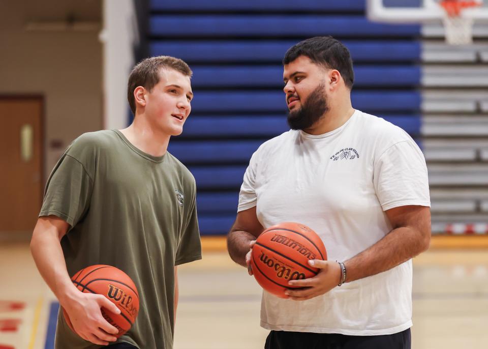 Winnacunnet High School boys basketball assistant coach Seth Provencher talks with junior Andrew Simmons during Tuesday's practice.
