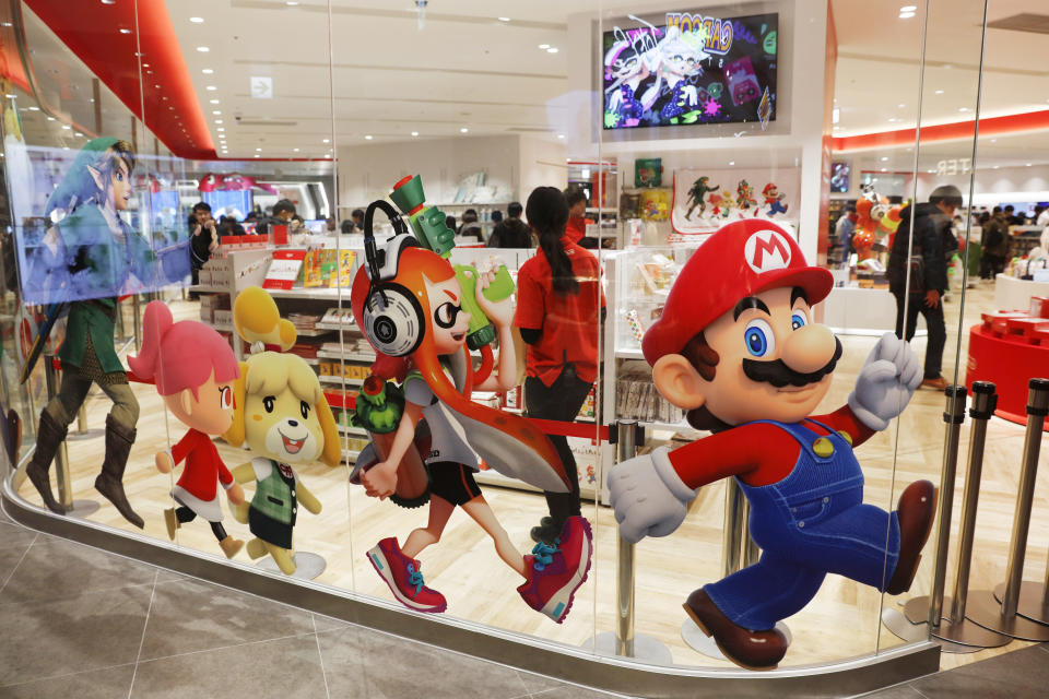 FILE - In this Jan. 23, 2020, file photo, Nintendo characters, including Mario, right, are seen on a glass of its official store in Tokyo. Nintendo Co.’s profit for the fiscal year ended in March jumped 86% on healthy sales of the Switch handheld machine as people staying at home over the pandemic turned to video games. (AP Photo/Jae C. Hong, File)