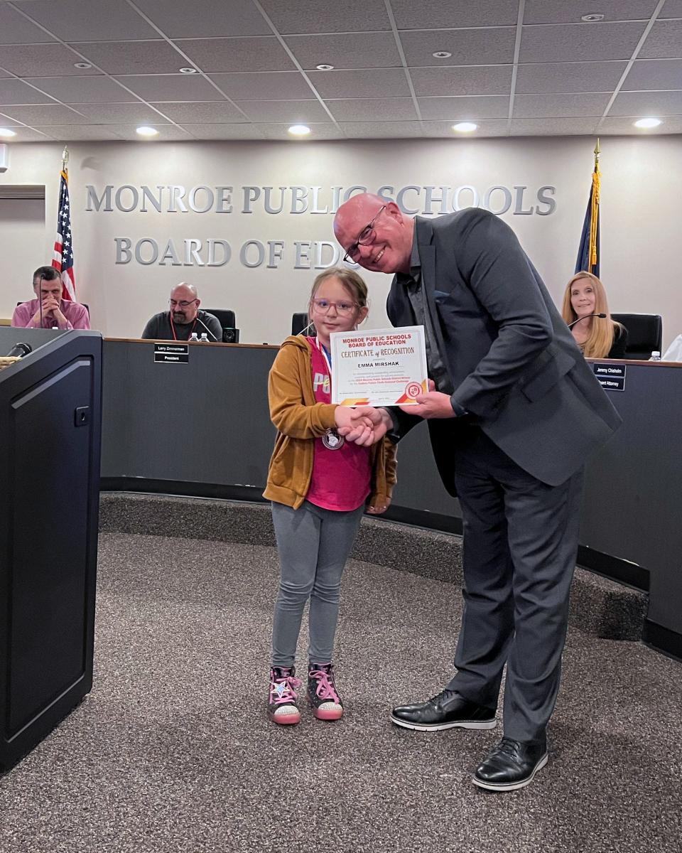 Emma, shown with Monroe Public Schools' Superintendent Andrew Shaw, received an award at last week's board meeting.