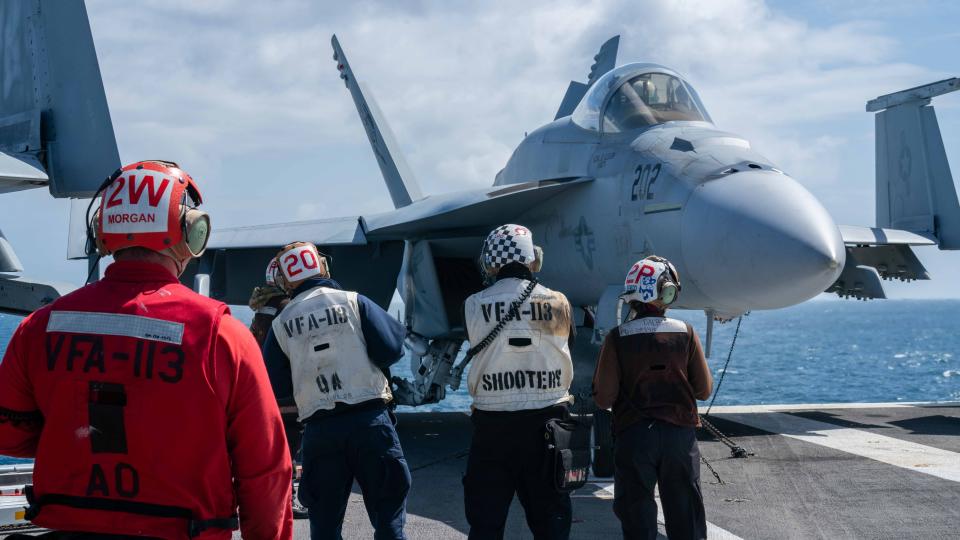 Sailors prepare to taxi an F/A-18E Super Hornet on the flight deck of USS Carl Vinson.