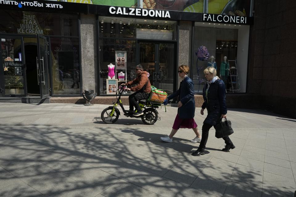 People walk past an opening boutique Calzedonia in Tverskaya street in Moscow, Russia, Thursday, April 27, 2023. When Russia invaded Ukraine, companies were quick to respond, some announcing they would get out of Russia immediately, others vowed to curtail sales and new investment. More than a year later, it’s clear: Leaving Russia isn't as easy as the first announcements might have made it seem. (AP Photo/Alexander Zemlianichenko)
