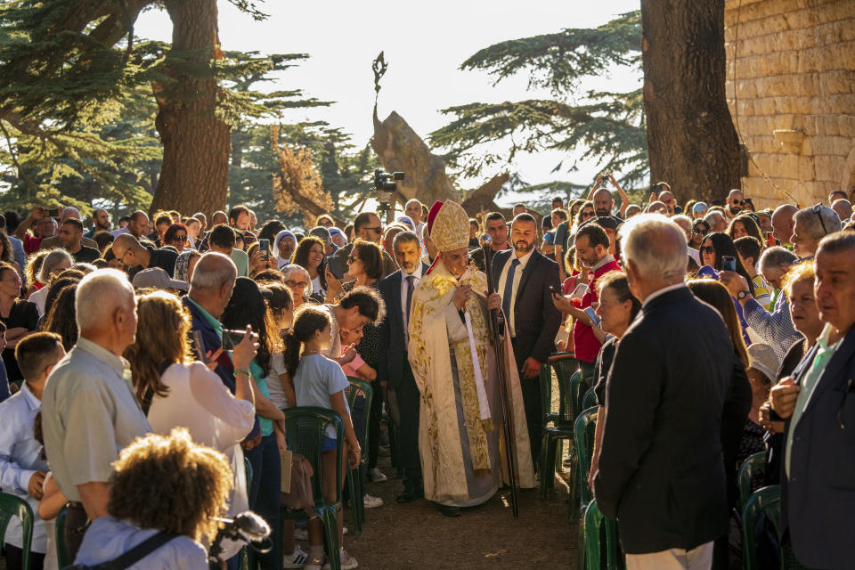 People greet Lebanese Maronite Christian Patriarch Beshara al-Rai, center, as he arrives to start the sermon to commemorate the Feast of the Transfiguration in the Cedars of God forest, in the northeast mountain town of Bcharre, Lebanon, Saturday, Aug. 5, 2023. For Lebanon's Christians, the cedars are sacred, these tough evergreen trees that survive the mountain's harsh snowy winters. They point out with pride that Lebanon's cedars are mentioned 103 times in the Bible. (AP Photo/Hassan Ammar)