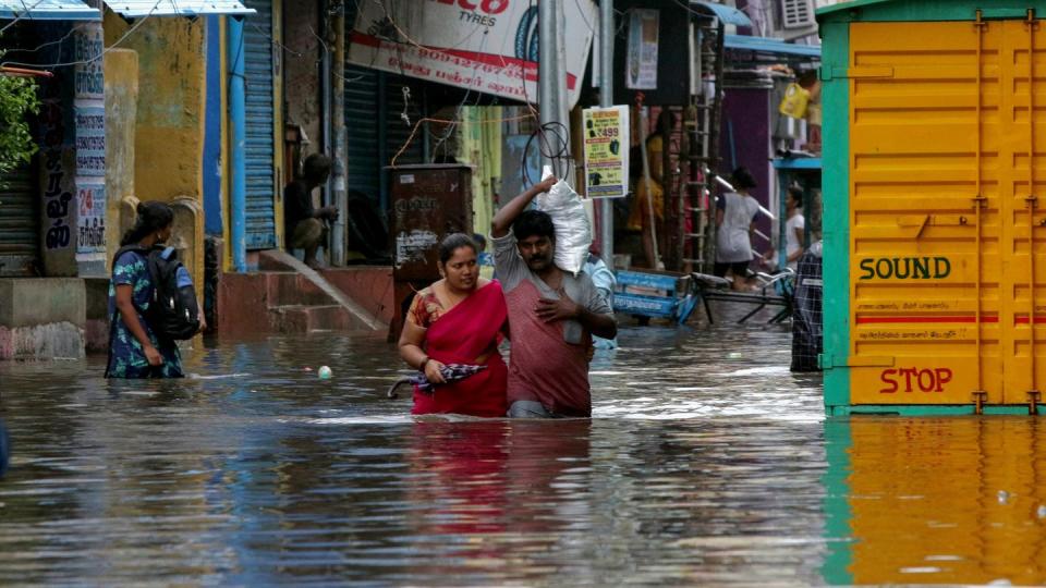 Menschen waten durch eine überflutete Straße in Chennai. Sturm «Nivar» soll viel Regen bringen und Windgeschwindigkeiten bis 130 km/h erreichen.
