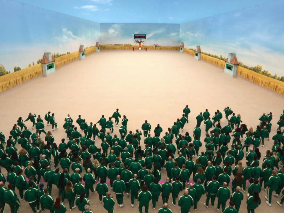 A crowd in green running across a room in "Squid Game: The Challenge"