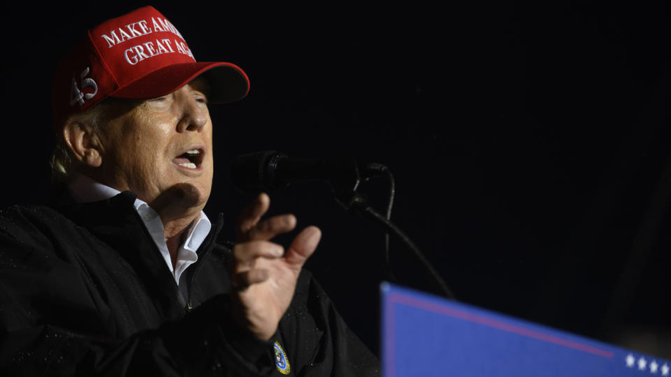 Former President Donald Trump holds forth, wearing a Make America Great Again baseball cap.