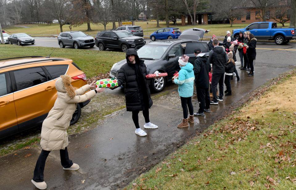 Family, friends and community members pass presents for the Buzzelli Family on Saturday, Dec. 23, 2023, in Alliance as part of the Sally & Assoc. Auto Sales, Inc., Christmas car giveaway.