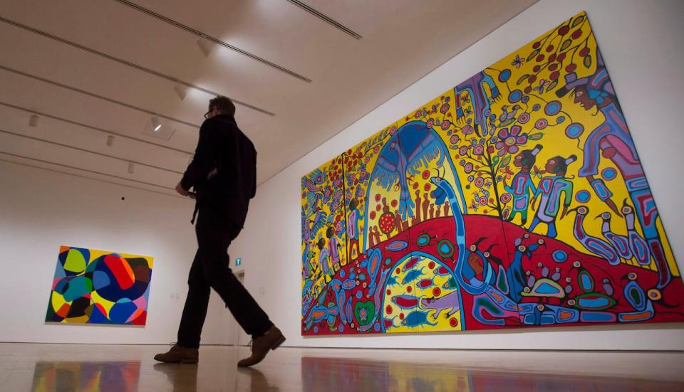 A reporter walks past 'Androgyny' by Norval Morrisseau (right) and 'Tweaker' by Lawrence Paul Yuxweluptun during a media tour of the Canadian and Indigenous Art: 1968 to Present at the National Gallery of Canada's contemporary art galleries Tuesday May 2, 2017, in Ottawa. 