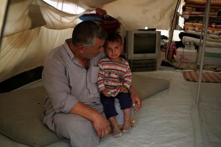 A man who had fled from Mosul sits with his son Ibrahim, 2, who was born under Islamic State rule and has no identity documents recognised by Iraqi authorities, in Debaga refugee camp, Iraq November 10, 2016. REUTERS/Zohra Bensemra