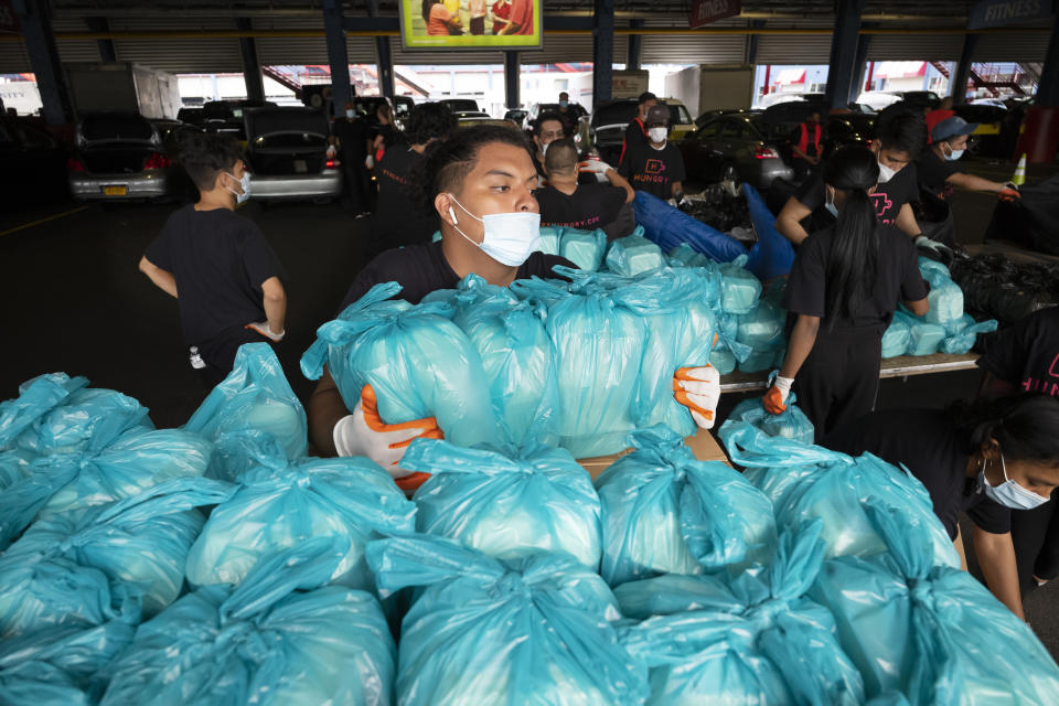 A worker moves bags of prepackaged meals to a sorting table where they will be loaded into insulated containers for delivery to needy families in New York, Tuesday, July 7, 2020. Catering startup HUNGRY originally served well-heeled office workers but with the downturn of the economy during the coronavirus pandemic it's now feeding the stuck-at-home elderly and low-income kids.(AP Photo/Mark Lennihan)