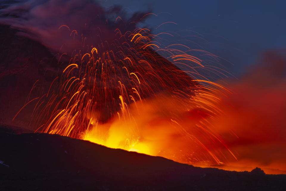 In this photo taken on Thursday, May 30, 2019 and made available Friday, May 31, 2019 Mount Etna volcano spews lava during an eruption. Mount Etna in Sicily has roared back into spectacular volcanic action from Thursday morning, sending up plumes of ash and spewing lava. (AP Photo/Salvatore Allegra)