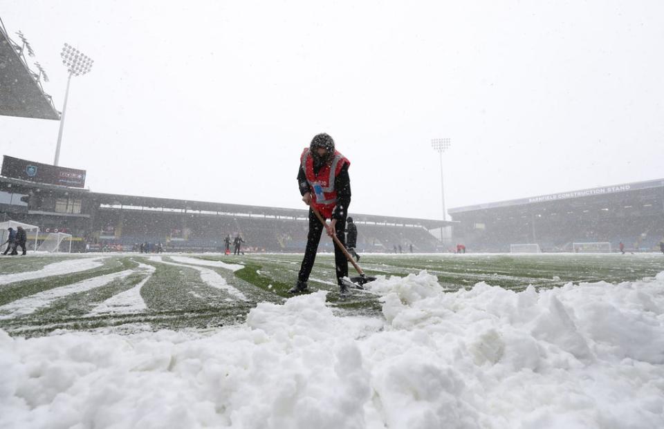 Snow is cleared from the pitch before the Premier League match at Turf Moor, Burnley (PA)