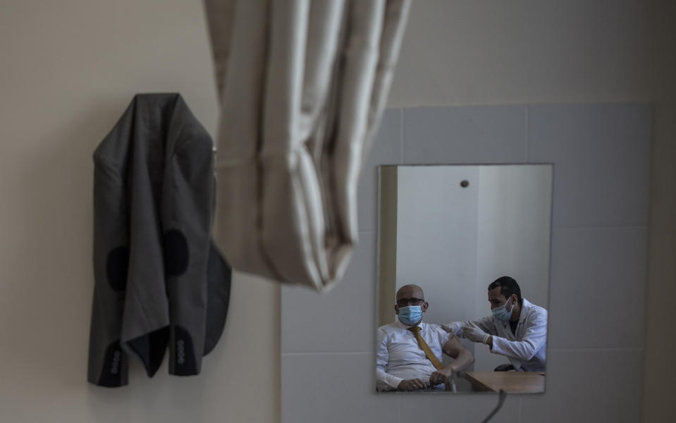 A Palestinian man receives a shot of the Russian-made Sputnik V coronavirus vaccine, at an UNRWA clinic in Gaza City, Wednesday, March 17, 2021. The Palestinian Authority says it will receive 62,000 coronavirus vaccine doses through a World Health Organization partnership designed to help poor countries. (AP Photo/Khalil Hamra)