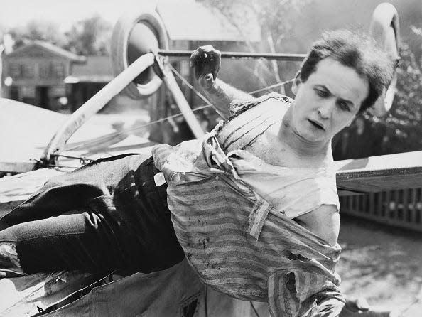 harry houdini laying sideways out of a vehicle.