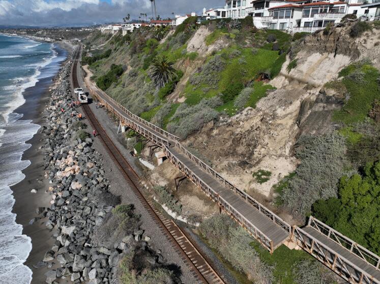 San Clemente, CA - January 25: An aerial view of Metrolink workers surveying a landslide that partially covered the train tracks and damage the Mariposa Trail Bridge, north of the San Clemente Pier in San Clemente Thursday, Jan. 25, 2024. Passenger rail service between the Laguna Niguel/Mission Viejo and Oceanside stations was suspended due to boulders and debris falling onto the tracks caused by a landslide damaging the Mariposa Trail Bridge in San Clemente, Metrolink announced, and it was uncertain today when service would resume. (Allen J. Schaben / Los Angeles Times)