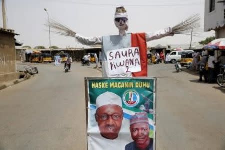 A dummy made out of sticks of a broom, the All Progressives Congress (APC) party's symbol, is placed next to an election poster campaigning for APC's presidential candidate Muhammadu Buhari, along a road in Katsina city March 26, 2015. REUTERS/Akintunde Akinleye
