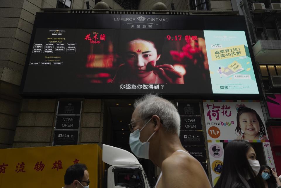 People walk past a huge TV screen showing movie "Mulan" at a downtown street in Hong Kong Thursday, Sept. 17, 2020. The remake of “Mulan” struck all the right chords to be a hit in the key Chinese market. Disney cast beloved actresses Liu Yifei as Mulan and removed a popular dragon sidekick in the original to cater to Chinese tastes. (AP Photo/Vincent Yu)