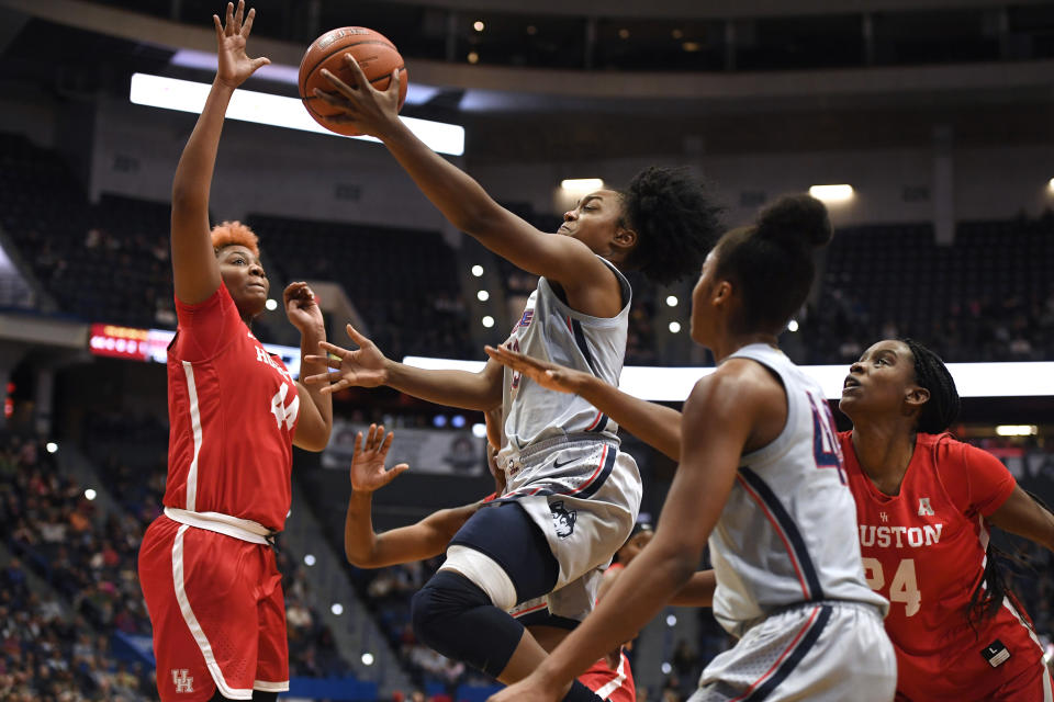 Connecticut's Christyn Williams, center, goes up for a basket as Houston's Jazmaine Lewis, left, and Houston's Maya Jones, right, defend, in the second half of an NCAA college basketball game, Saturday, Jan. 11, 2020, in Hartford, Conn. (AP Photo/Jessica Hill)
