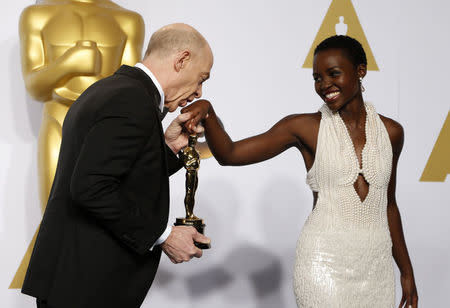 J.K. Simmons, winner of the award for best supporting actor nominee for his role in "Whiplash," kisses the hand of presenter Lupita Nyong'o during the 87th Academy Awards in Hollywood, California February 22, 2015. REUTERS/Lucy Nicholson