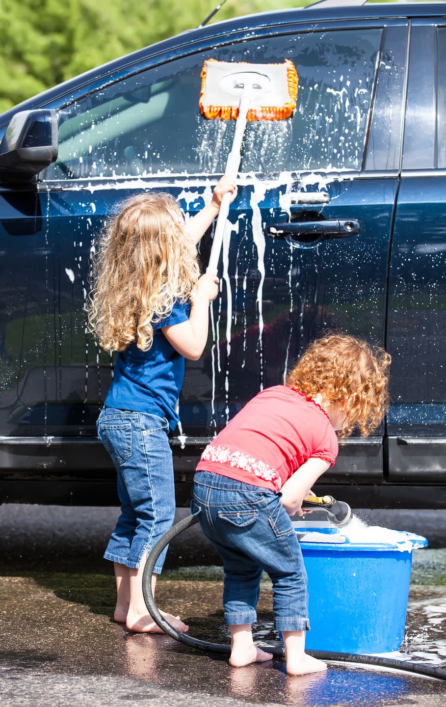 summer activities two young girls washing blue car