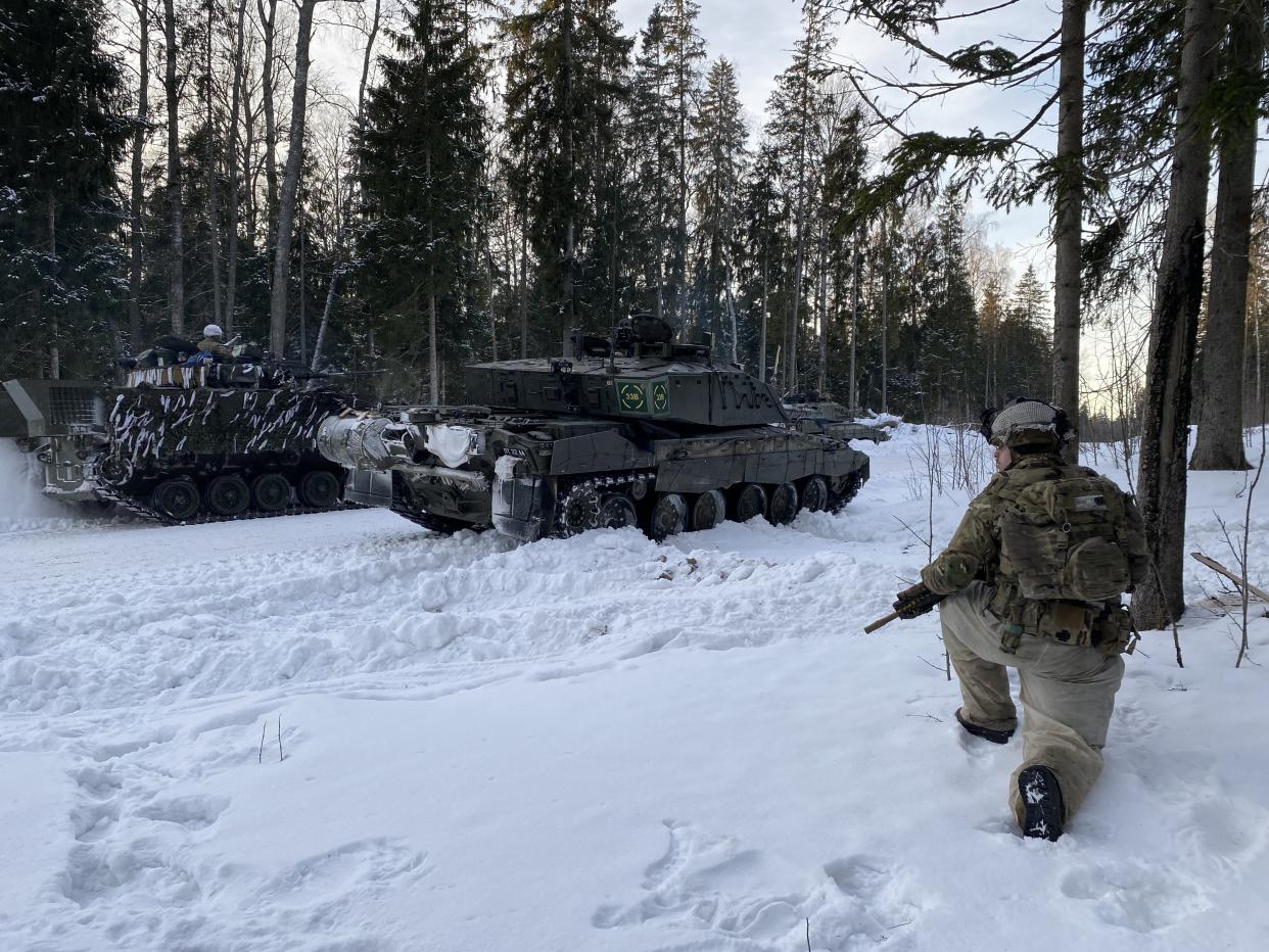 A soldier kneels in the snow in the forest next to a British Challenger 2 in Estonia earlier in February. (PA)