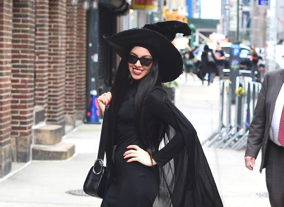 Aubrey, dressed as a witch, smiles for a photo with her hand on her hip