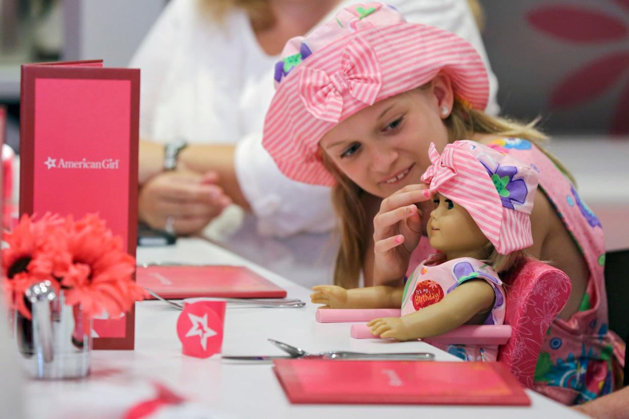 A young customer fixes her doll's hat while waiting in the American Girl store's diner Saturday morning, June 22, 2013.