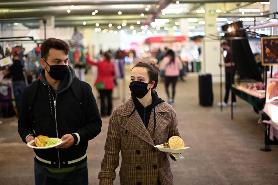 People wearing protective face masks looks for a seat to eat their lunch in The Old Truman Brewery's markets in east London on September 26, 2020, as Londoners live with new restrictions, introduced to combat the spread of the novel coronavirus pandemic. - Britain has tightened restrictions to stem a surge of coronavirus cases, ordering pubs to close early and advising people to go back to working from home to prevent a second national lockdown. (Photo by DANIEL LEAL-OLIVAS / AFP) (Photo by DANIEL LEAL-OLIVAS/AFP via Getty Images)
