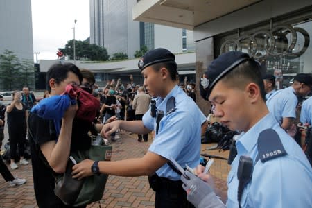 A police officer checks the bag of a pedestrian following a day of violence in Hong Kong