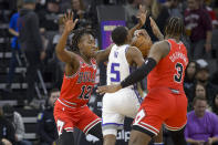 Chicago Bulls guard Ayo Dosunmu (12) and Andre Drummond (3) guard Sacramento Kings guard De'Aaron Fox (5) during the first quarter of an NBA basketball game in Sacramento, Calif., Sunday, Dec. 4, 2022. (AP Photo/Randall Benton)