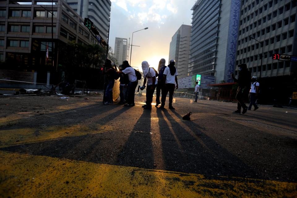 Demonstrators prepare to throw molotov bombs against Bolivarian National Police officers during clashes in Caracas, Venezuela, Thursday, March 6, 2014. A National Guardsman and a civilian were killed earlier today in a clash between residents of a Caracas neighborhood and armed men who tried to remove a barricade, Venezuelan officials said. (AP Photo/Fernando Llano)