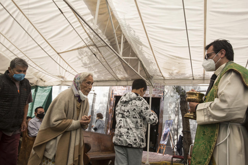 Catholics line up to receive Communion from Rev. Adrian Vazquez during an outdoor Mass held under a tent just outside the quake-damaged Our Lady of the Angels church in Mexico City, Sunday, Aug. 7, 2022. Set in the working-class residential neighborhood of Guerrero and carrying one of the Virgin Mary's titles, Our Lady of the Angels’ history dates to the end of the 16th century. (AP Photo/Ginnette Riquelme)