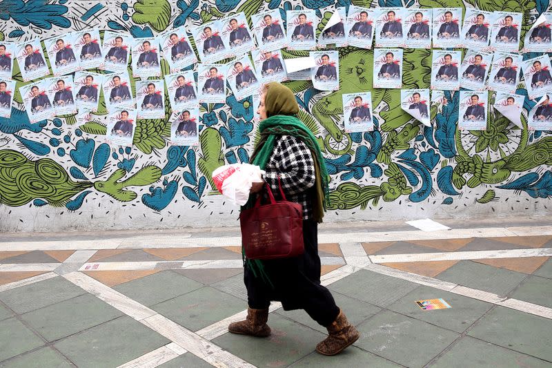 A woman walks past parliamentary election campaign posters in Tehran