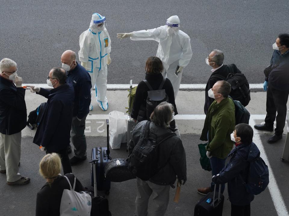 A worker in protective coverings directs members of the World Health Organization (WHO) team on their arrival at the airport in Wuhan in central China's Hubei province (AP)