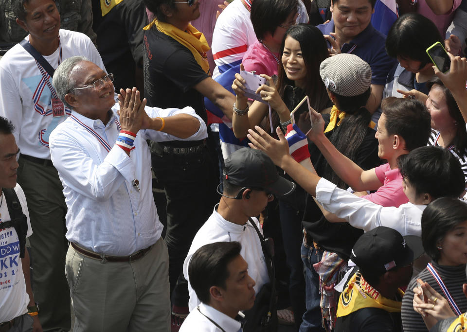 Thai anti-government protest leader Suthep Thaugsuban, left, greets cheering supporters during a march in Bangkok, Thailand Saturday, Jan. 25, 2014. Thailand's ruling party has questioned the reasoning behind a court decision allowing next month's general election to be postponed, but held open the possibility that it might agree to put off the polls if its political rivals agree to recognize the legitimacy of a new vote. (AP Photo/Apichart Weerawong)