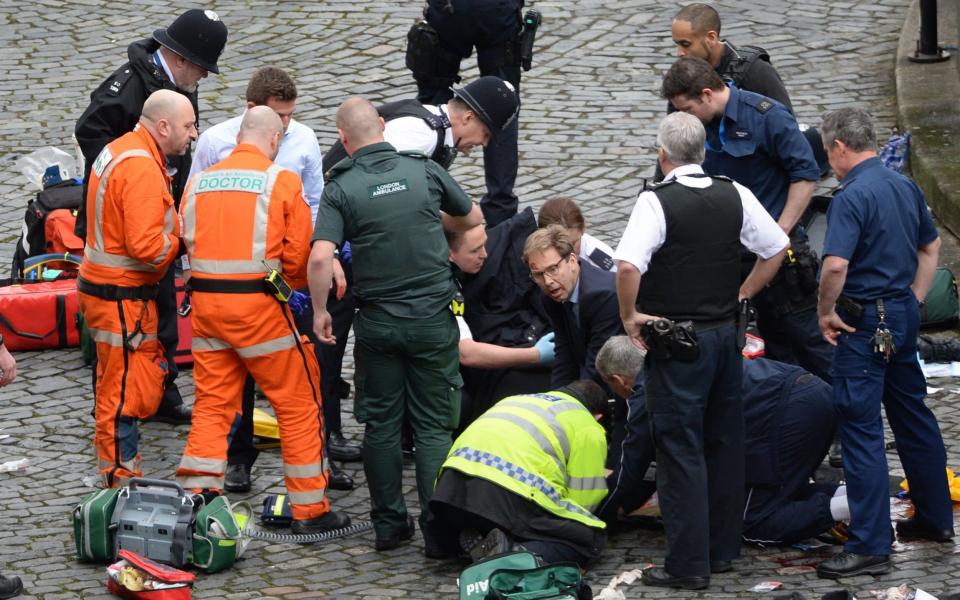 Conservative MP Tobias Ellwood (centre) helps emergency services attend to a police officer - Credit: Stefan Rousseau/PA