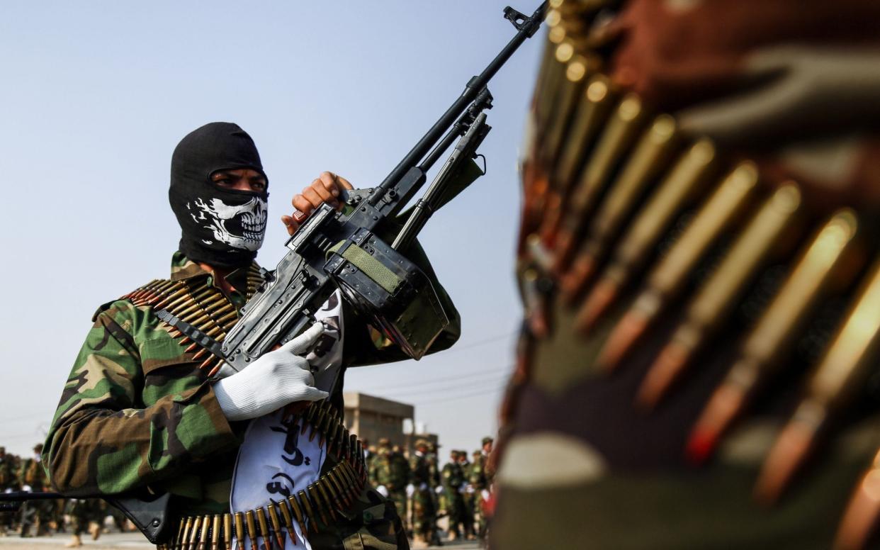 Member of the Hashed al-Shaabi (Popular Mobilisation) paramilitaries, marching with machine guns in a military parade in the holy shrine city of Najaf in central Iraq - AFP