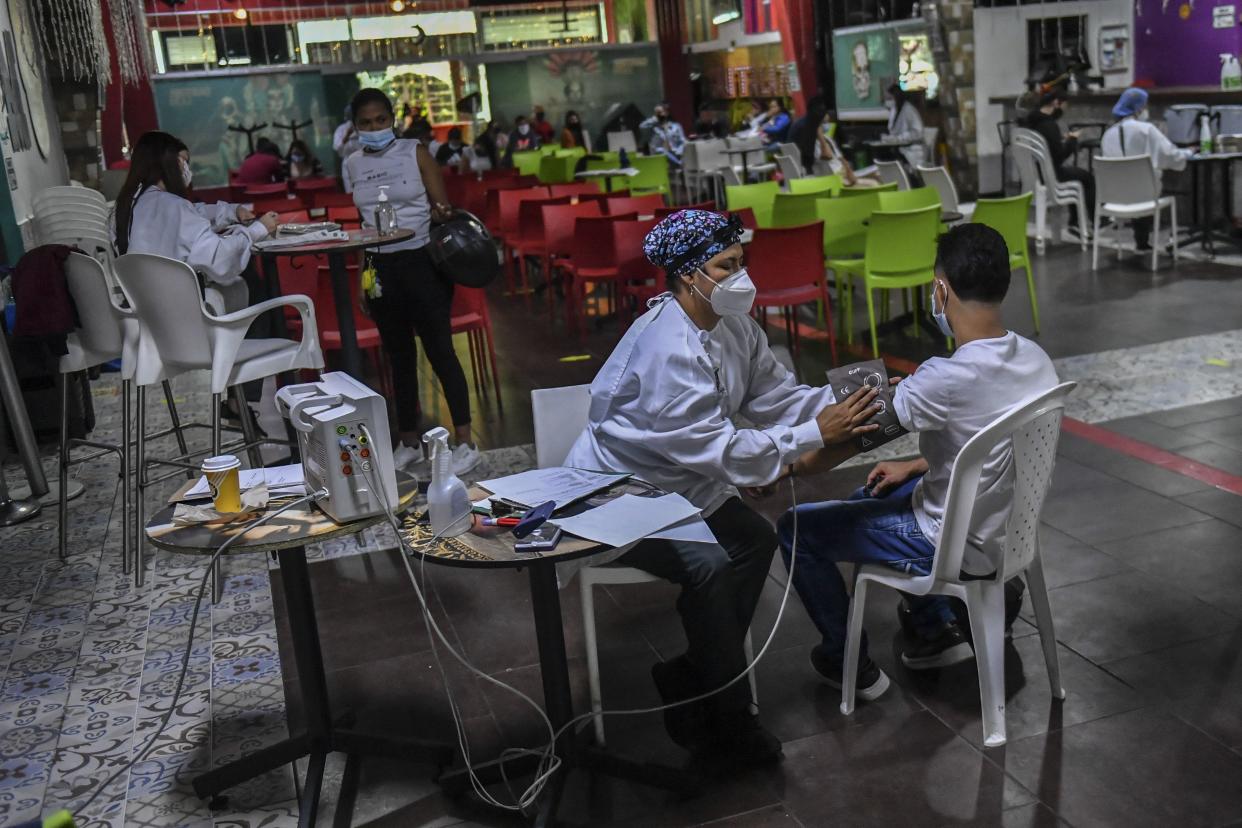 A nurse checks the pressure of a man who received the Moderna vaccine against COVID-19 at a vaccination point in the La Cantina bar in Medellin, Colombia on Aug. 11, 2021. People over 18 years of age who work in the gastronomic sector are being vaccinated as part of a program sponsored by the private sector.