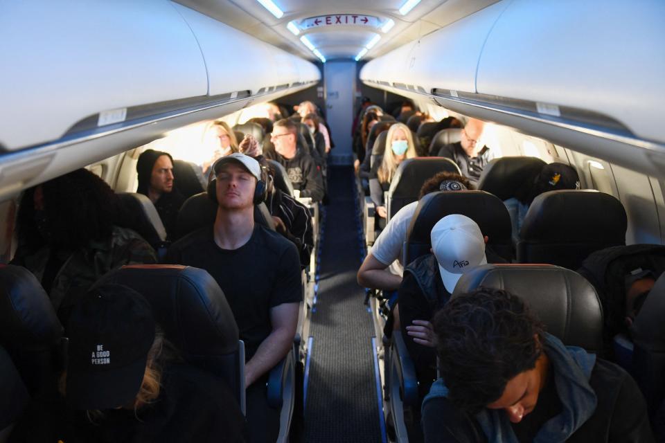 Airline passengers, some not wearing face masks following the end of Covid-19 public transportation rules, sit during a American Airlines flight operated by SkyWest Airlines from Los Angeles International Airport (LAX) in California to Denver, Colorado on April 19, 2022.
