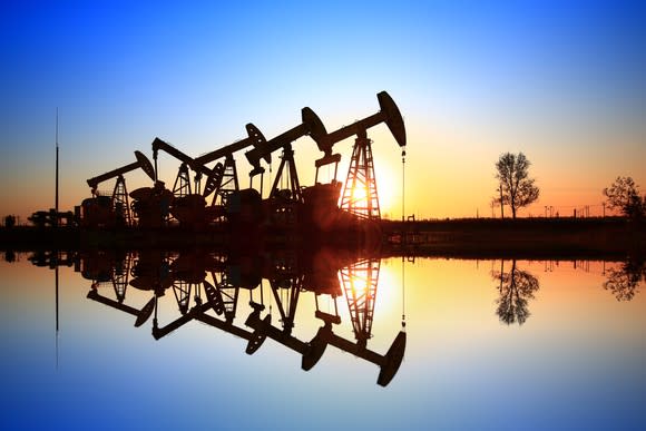 A row of oil pumps reflecting on the water.