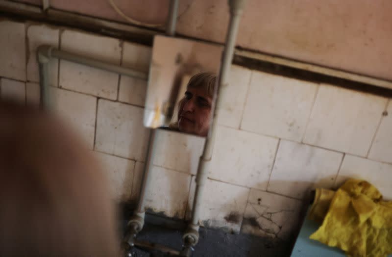 Tatyana Medvedenko, de 48 años, una persona con discapacidad visual se refleja en un espejo mientras lava los platos en la cocina comunitaria de un albergue para ciegos, en medio de la invasión rusa de Ucrania, en Jarkov
