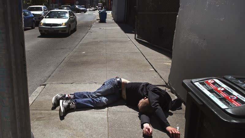 In this April 26, 2018, file photo, a man lies on the sidewalk beside a trash recycling bin in San Francisco. California Gov. Gavin Newsom announced Friday, April 21, 2023, that the state highway patrol and National Guard will provide additional personnel and resources to help San Francisco battle its worsening fentanyl drug crisis. 