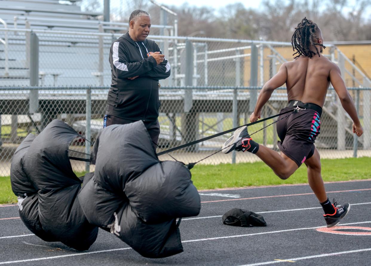 Manual track and field coach Harvey Burnett times his senior sprinter Lamello Gilbert during a recent practice at the South Peoria high school.