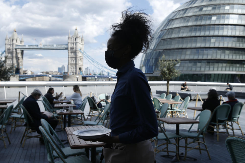 LONDON, ENGLAND - MAY 19: Waitress carries a plate in view of Tower Bridge at Tavolino Bar & Kitchen on May 19, 2021 in London, England. Although indoor drinking and dining were permitted in England with yesterday's Covid-19 lockdown easing, there remain social distancing rules and restrictions on party size that prevent many restaurants from returning to full capacity. The next phase of reopening, when all limits on social contact are due to be lifted on June 21, is vital to the recovery of the hospitality business. (Photo by Hollie Adams/Getty Images)