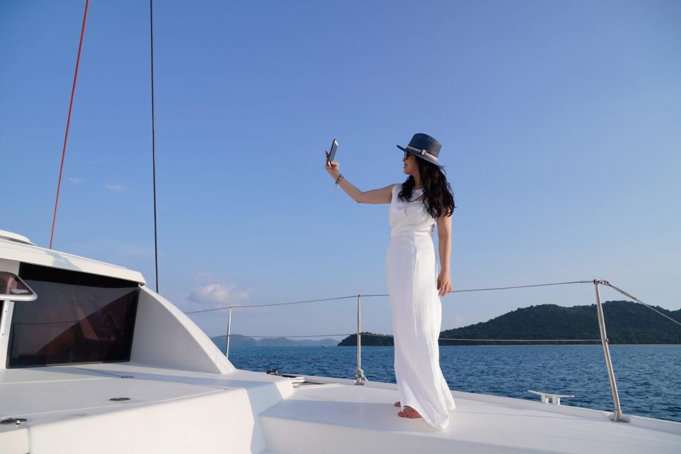 Eine Frau macht ein Selfie auf einer Jacht. (Symbolfoto). - Copyright: Kamon Supasawat/Getty Images