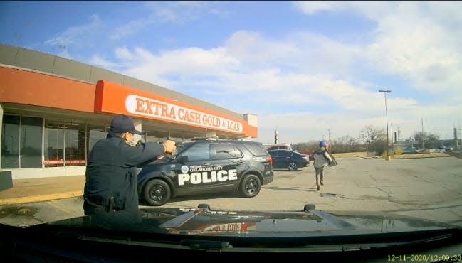 An image captured from a camera inside a police car shows Oklahoma City Police Sgt. Clifford Holman firing at Bennie Edwards as he runs away from officers.