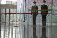 FILE - In this March 12, 2020, file photo, Chinese paramilitary policemen stand on duty behind a barrier at the Capital International Airport terminal 3 in Beijing. President Donald Trump has repeatedly credited his February ban on travelers from mainland China as his signature move against the advance of the coronavirus pandemic -- a “strong wall” that allowed only U.S. citizens inside, he boasted in May. But Trump’s wall was more like a sieve. Exempted were thousands of residents of the Chinese territories of Hong Kong and Macau. (AP Photo/Ng Han Guan, File)