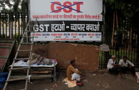 Labourers sit next to a banner after a protest against the implementation of the goods and services tax (GST) on textiles, in the old quarters of Delhi, India June 29, 2017. The banner reads “Remove GST – save business”. REUTERS/Adnan Abidi