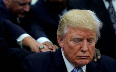 FILE PHOTO: Faith leaders place their hands on the shoulders of U.S. President Donald Trump as he takes part in a prayer for those affected by Hurricane Harvey in the Oval Office of the White House in Washington, U.S., September 1, 2017. REUTERS/Kevin Lamarque/Files