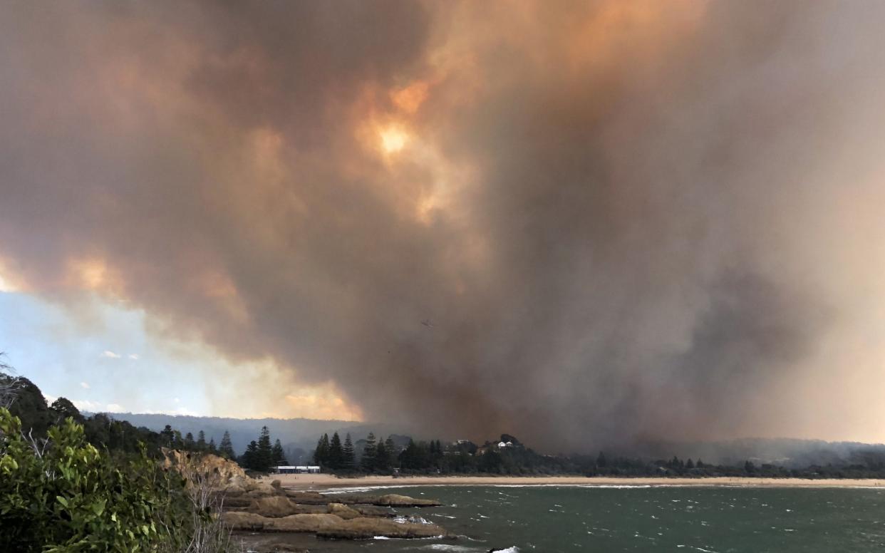 Smoke rising from fires in the village of Tathra on the south coast of New South Wales, where up to 70 homes were razed - AFP